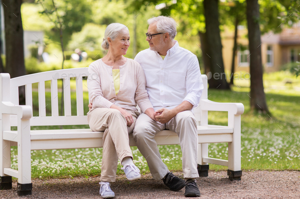 happy senior couple sitting on bench at park