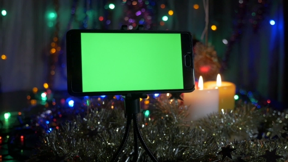 New Year's Background, in the Foreground a Smartphone with a Green Screen