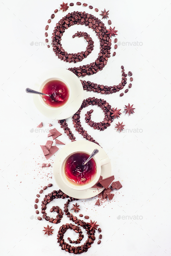 Coffee grains lying in the shape of a swirl with the cup, cinnamon, anise stars and chocolate