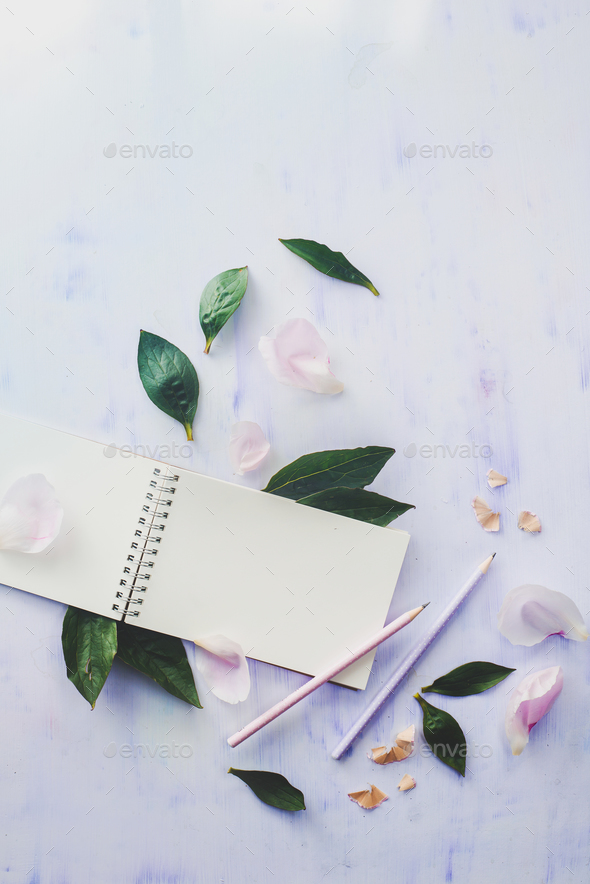 Minimal styled flat lay with peony flowers, petals and blank notebook on a white background