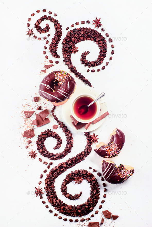 Coffee grains lying in the shape of a swirl with the cup, cinnamon, anise stars and donuts