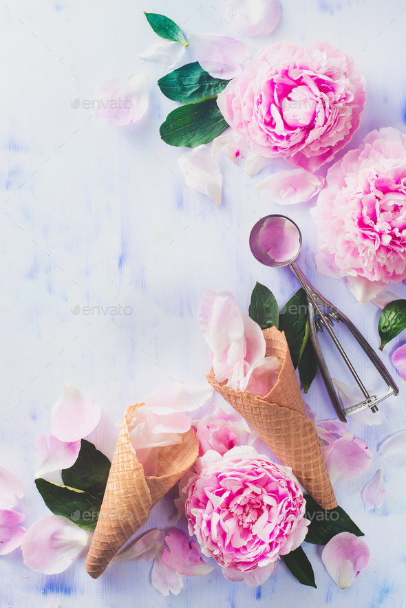 Minimal styled flatlay with peony flowers, petals, and waffle ice cream cones on a pastel background