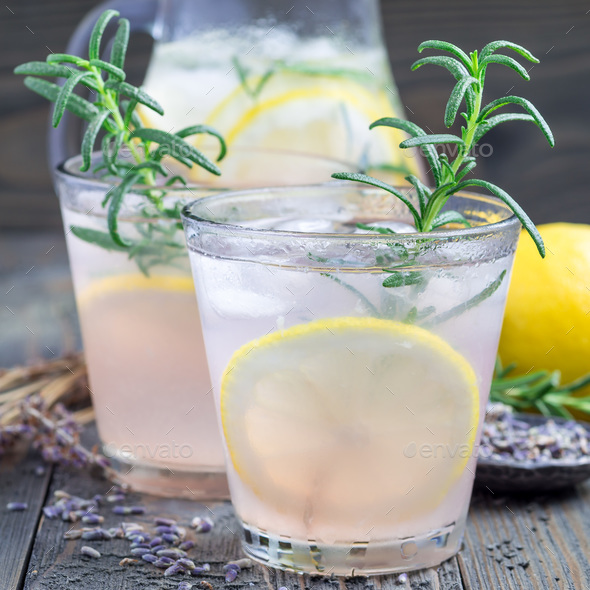 Homemade lemonade with lavender, fresh lemons and rosemary on a wooden background, square format