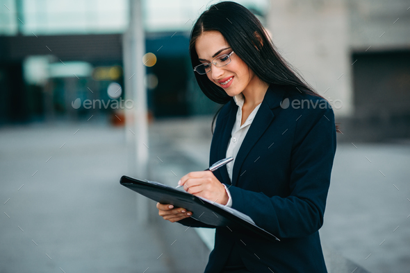Businesswoman in suit writing in notebook outdoor - Stock Photo - Images