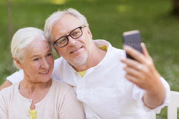senior couple taking selfie by smartphone at park