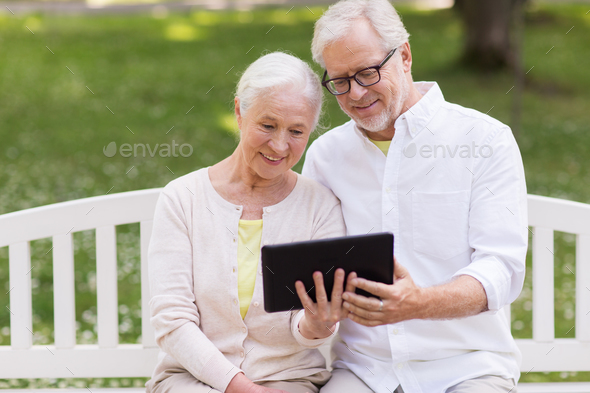 happy senior couple with tablet pc at summer park