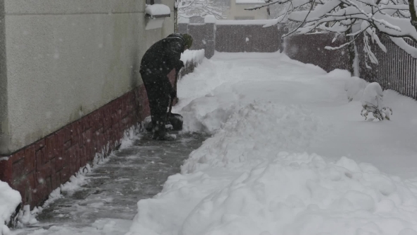 Man Clears the Snow with a Shovel