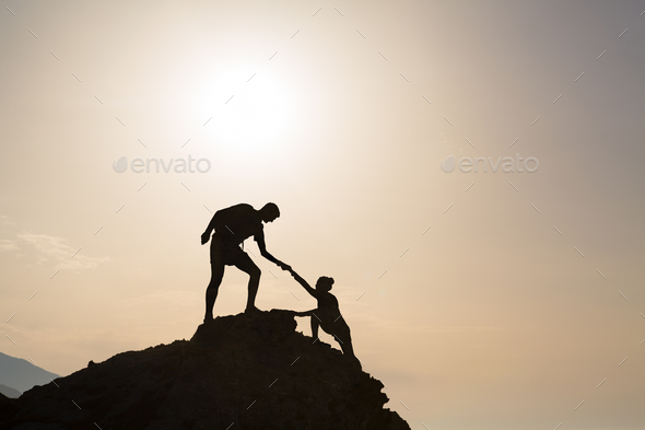 Teamwork couple helping hand trust in inspiring mountains