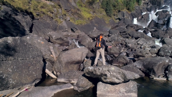 Aerial View of Man Standing in Front of a Waterfall River with Rocks, Trees