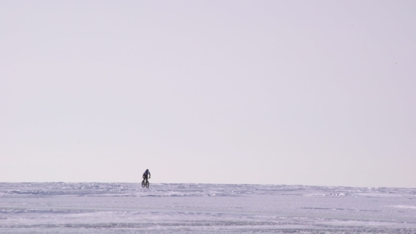 a Man Riding a Bicycle Across a Frozen Lake