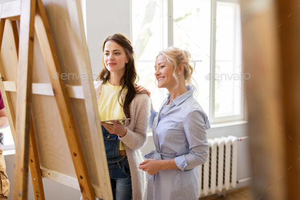 artists discussing painting on easel at art school - Stock Photo - Images