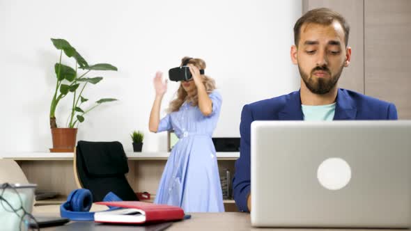 Beautiful Woman Exploring Virtual Reality While Her Boyfriend Works on the Computer alt