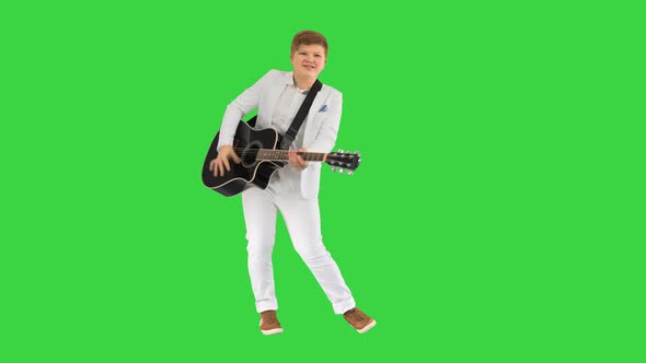 Boy in White Playing Acoustic Guitar and Dancing on a Green Screen, Chroma Key. alt