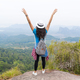 Tourist Girl With Backpack Standing On Mountain Top Raised Hands Back Rear View Enjoy Beautiful - PhotoDune Item for Sale