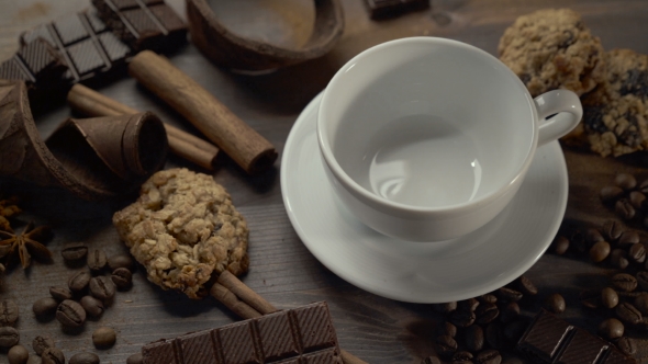 Cup of Hot Coffee with Cinnamon Sticks, Chocolate Slices and Cookies on Wooden Table