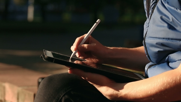 Designer Drawing Sketch On Tablet Using Stylus at Park