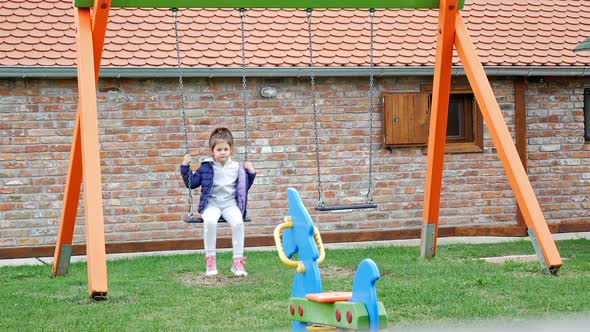 Small Caucasian Girl Swinging On Outdoor Playground