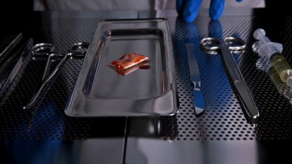 Surgeon Puts a Small Bag of Drugs on the Tray After Surgery alt