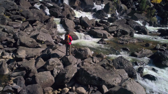 Aerial View of Man Standing in Front of a Waterfall River with Rocks, River