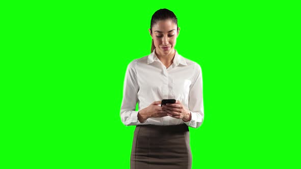 a Caucasian woman in suit using a phone in a green background