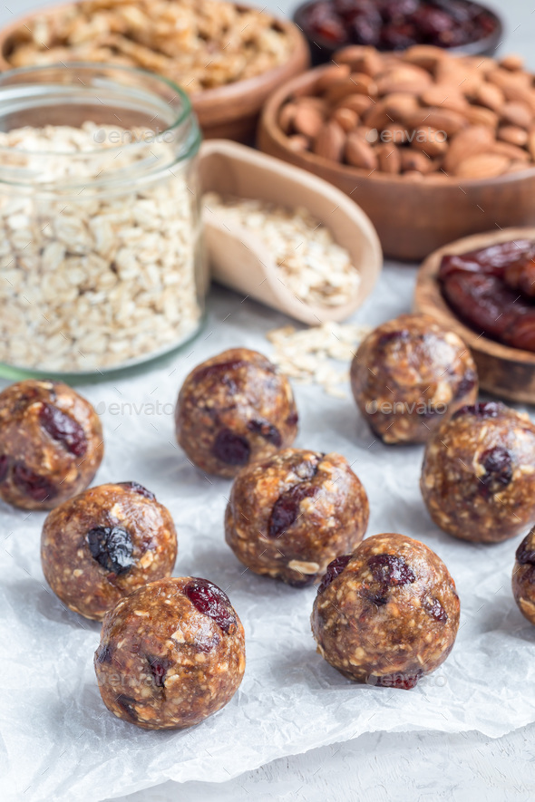 Healthy energy balls with cranberries, nuts, dates and rolled oats on parchment, vertical