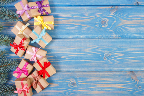 Gifts with ribbons for Christmas and spruce branches, copy space for text on old blue plank - Stock Photo - Images