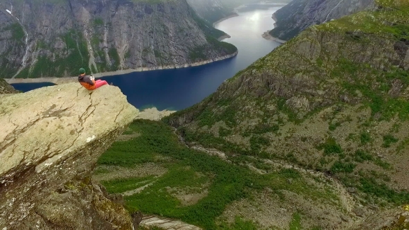 Norway. Guy and Girl Sitting on the Edge of the Trolltunga