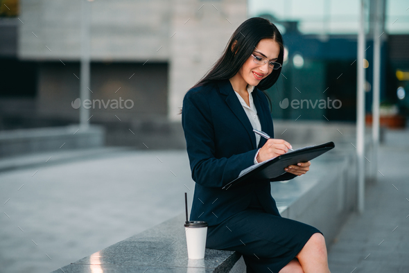 Businesswoman in suit writing in notebook outdoor - Stock Photo - Images