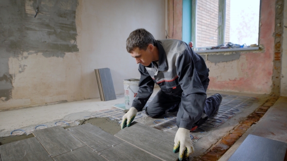 Master Is Installing Floor Ceramic Tile in a Room, Pressing Down and Leveling alt