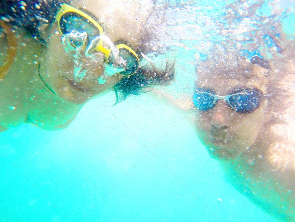 Swimming couple underwater with googles in the sea - Stock Photo - Images
