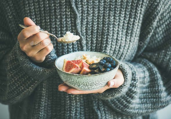 Woman in woolen sweater eating rice coconut porridge - Stock Photo - Images