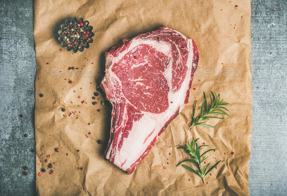 Raw beef steak rib-eye with seasoning on craft paper - Stock Photo - Images