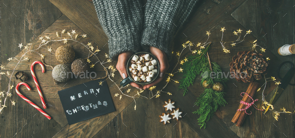 Flat-lay of greeting card, garland, woman's hands holding mug - Stock Photo - Images