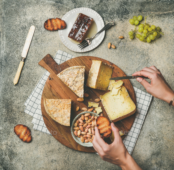 Cheese platter with female hands reaching to food, top view - Stock Photo - Images