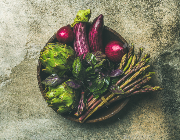 Flat-lay of green and purple vegetables on plate, grey background - Stock Photo - Images