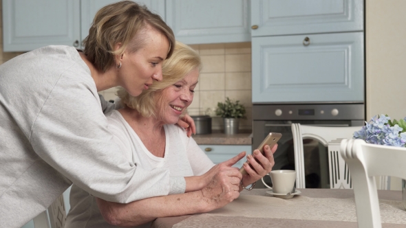 Elderly and Young Women Looks at Smartphone Screen at Home