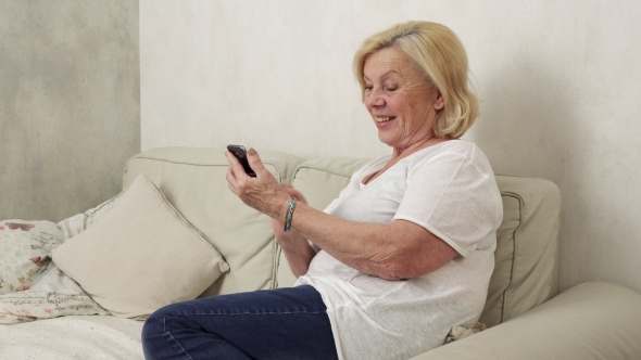 Happy Elderly Woman Uses a Smartphone
