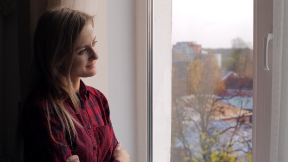 Beautiful Young Woman with Book Looking Out the Window and Smiling