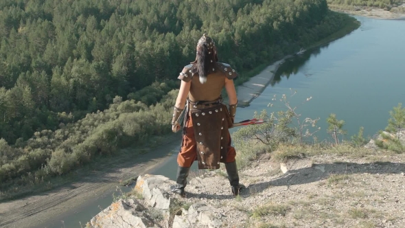 Young Archer Stands on Edge of Cliff on Summer Day. alt