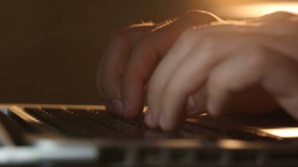 Hacker's Hands Typing Commands on Laptop Keyboard