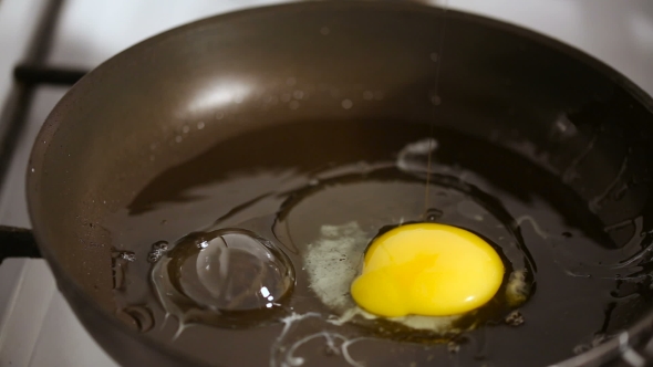 Breaking Egg and Cooking Scrambled Eggs on a Hot Frying Pan