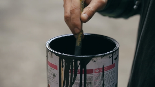 Painter Stirring a Paint in a Jar on the Street