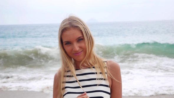Young Attractive Sexy Woman Looks at Camera and Smiles Against the Background in a Storm at Sea