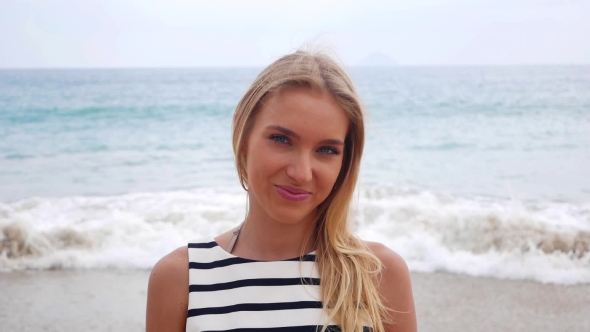 Young Attractive Sexy Woman Looks at Camera and Smiles Against the Background in a Storm at Sea