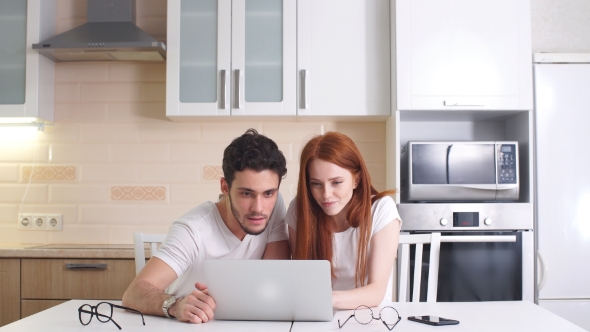 Young Business Couple Working with Laptop at Home in Kitchen. The Concept of Home Business alt