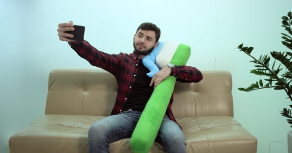 Young MAN Sitting on Sofa and Making Selfie with a Teeth Brush alt