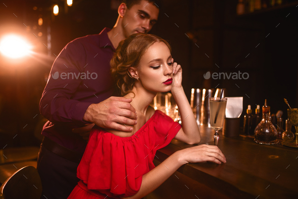 Woman in dress and man behind bar counter, flirt Stock Photo by NomadSoul1