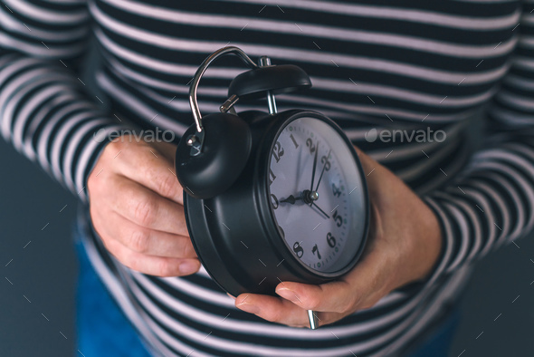 Woman winding retro alarm clock - Stock Photo - Images