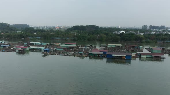Flying in over floating fish farming community in Bien Hoa on the Dong Nai river, Vietnam on a sunny alt