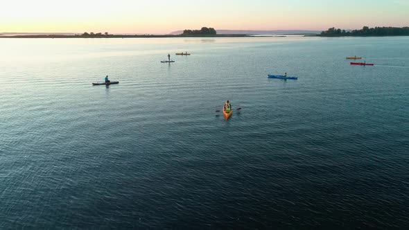 Aerial Drone Footage. A Group of Tourists Are Kayaking. Beautiful Sunrise Over River